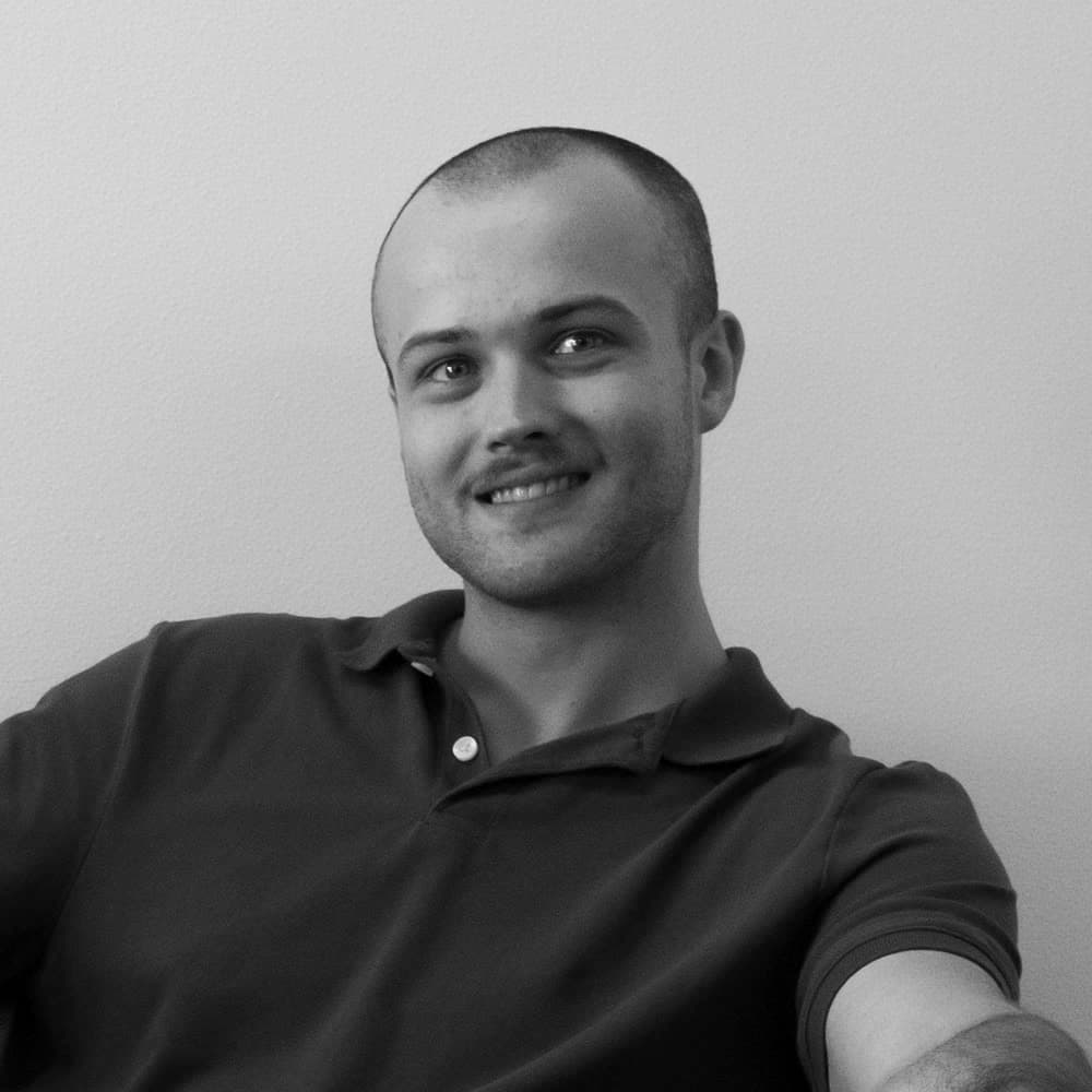 Black and white portrait of Tal Swicegood smiling, seated on a couch
